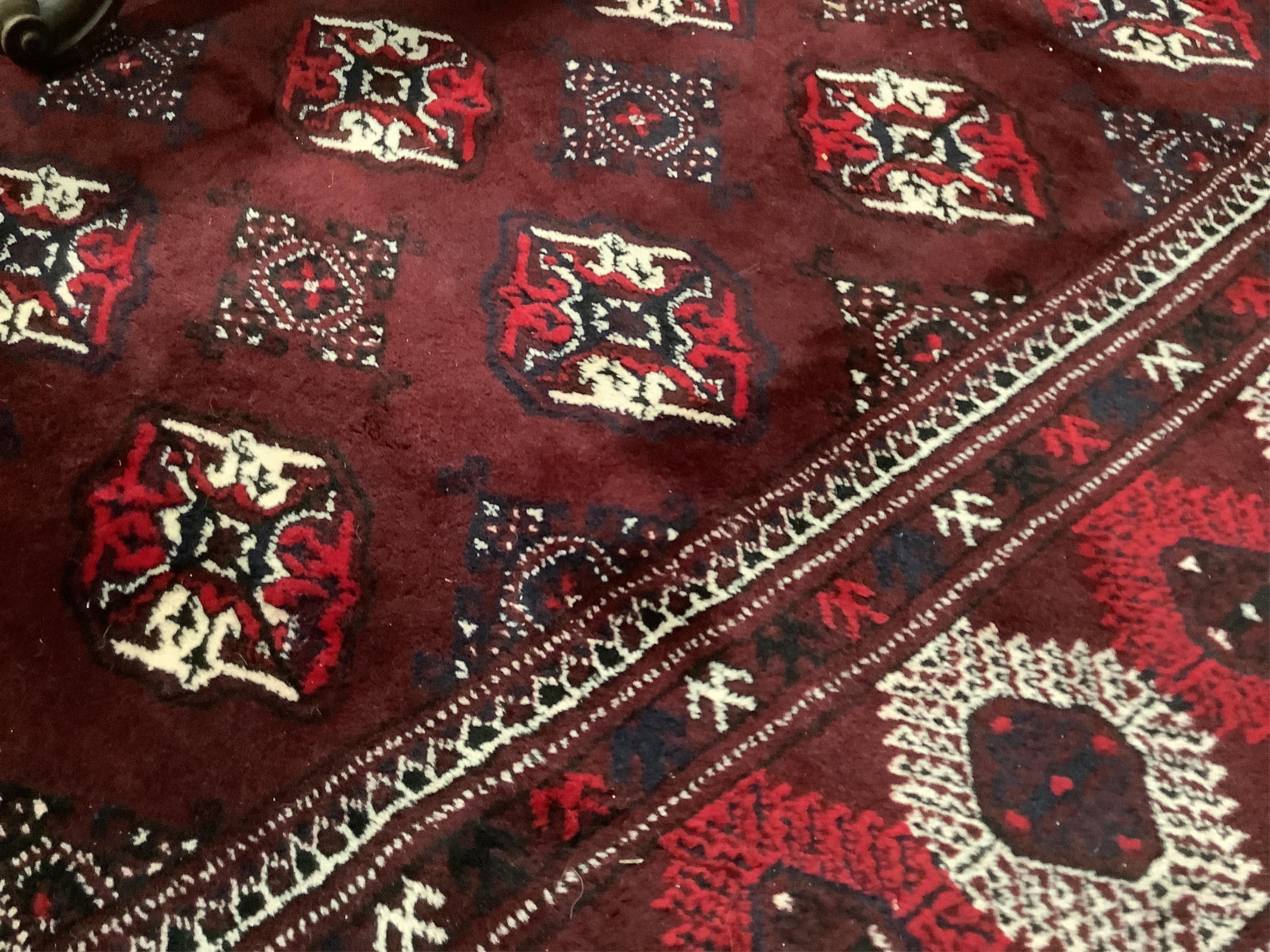 A Turkoman burgundy ground carpet, 386 x 234cm